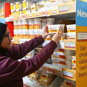 A person pulls a Standford Street Co. product from a Sainsbury shelf.